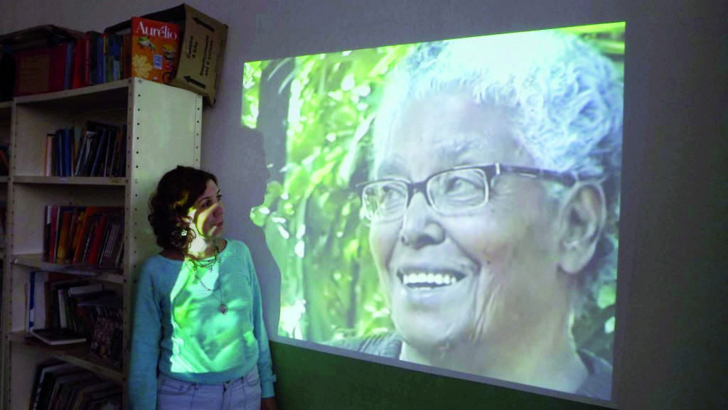 Junia Botelho, filha de Ruth, em frente à imagem da mãe, durante evento que homenageia a escritora (Foto: Reprodução)