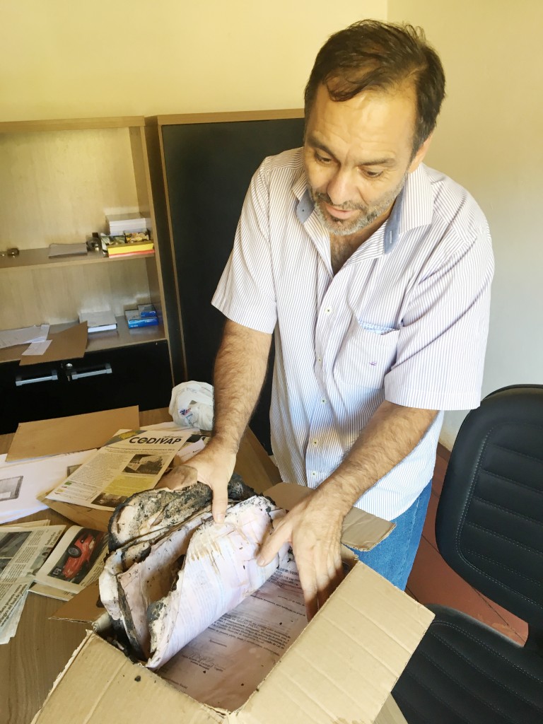 O prefeito Guilherme Carvalho mostra páginas parcialmente queimadas do material desenterrado pelos servidores 