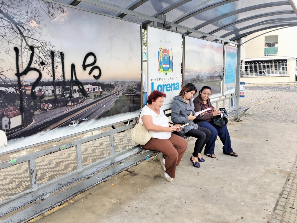 À espera do ônibus, trio lê em ponto na praça Conde de Moreira Lima; projetos buscam novos leitores (Foto: Jéssica Dias)