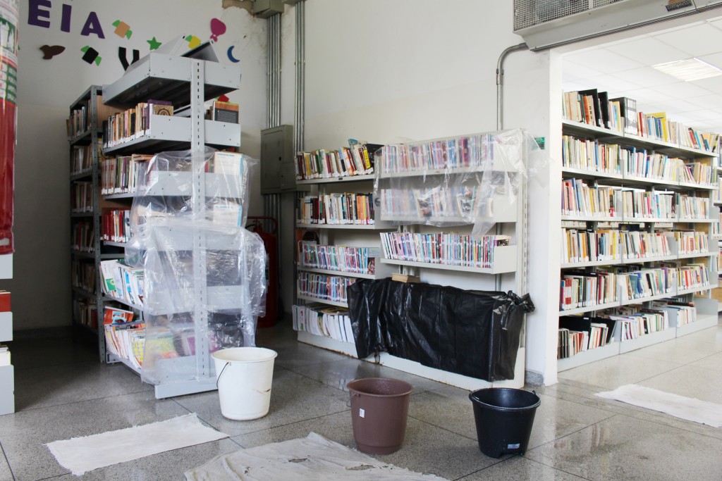 Funcionária da biblioteca separa livros após a chuva; Prefeitura recebe pedidos por reforma (Foto: Juliana Aguilera)