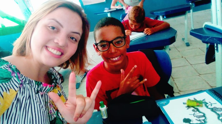 A professora Rayane Batista posa ao lado do pequeno Wellington de Souza, assistido por programa (Foto: Reprodução)